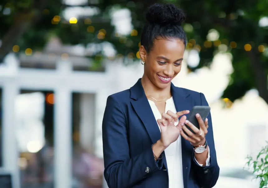 Kobieta biznesu z uśmiechem odbiera powiadomienie z systemu Business Messaging na smartfonie. Uśmiechnięta menedżerka odczytuje pilną wiadomość SMS i alert z komunikatora w trakcie pracy.