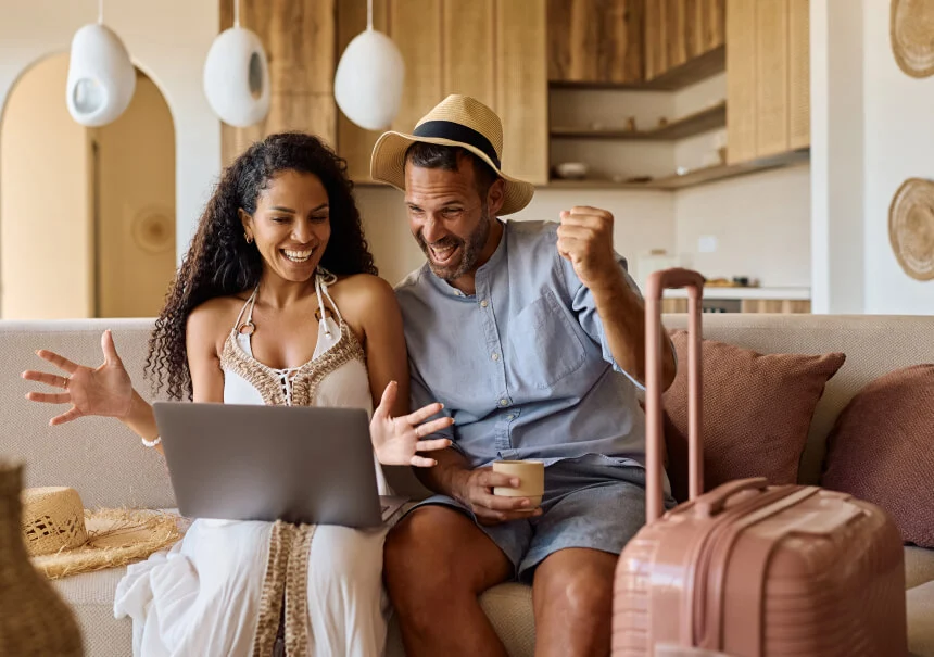Podekscytowana para cieszy się z rezerwacji wakacji życia na laptopie, po znalezieniu idealnej oferty na landing page’u biura podróży.